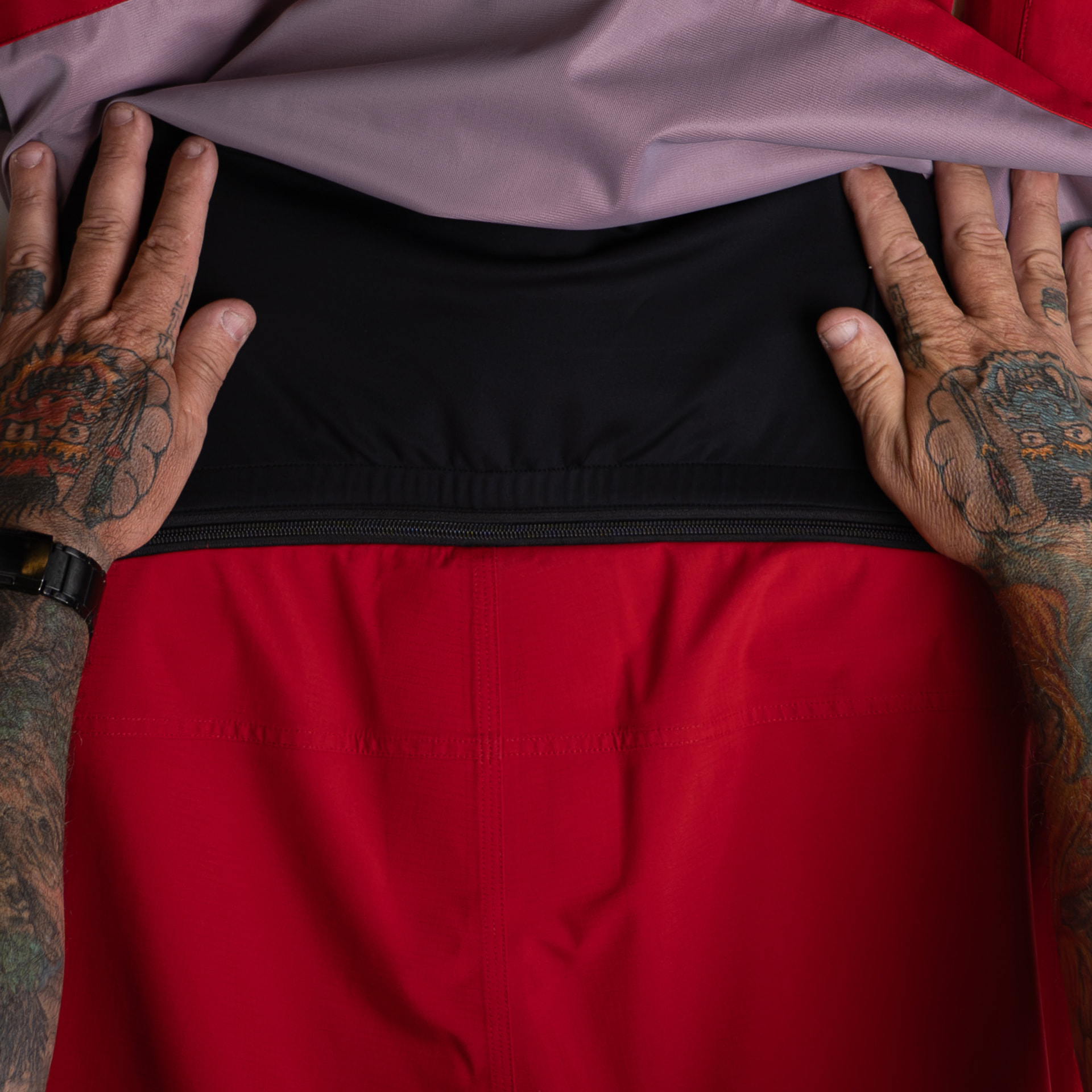 Hands pulling back the jacket lining to show the zip connection point